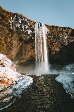 Seljalandsfoss şelale İzlanda'dan muhteşem manzara mavi gökyüzü ve kar ile açık bir günde.