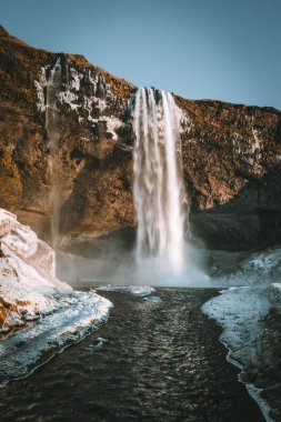 Seljalandsfoss şelale İzlanda'dan muhteşem manzara mavi gökyüzü ve kar ile açık bir günde.