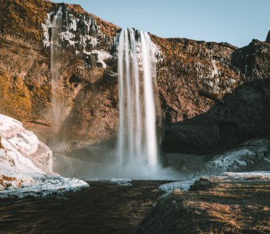 Seljalandsfoss şelale İzlanda'dan muhteşem manzara mavi gökyüzü ve kar ile açık bir günde.