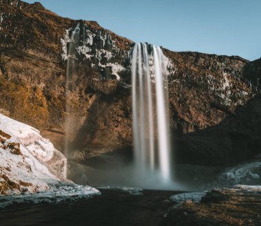 Seljalandsfoss şelale İzlanda'dan muhteşem manzara mavi gökyüzü ve kar ile açık bir günde.