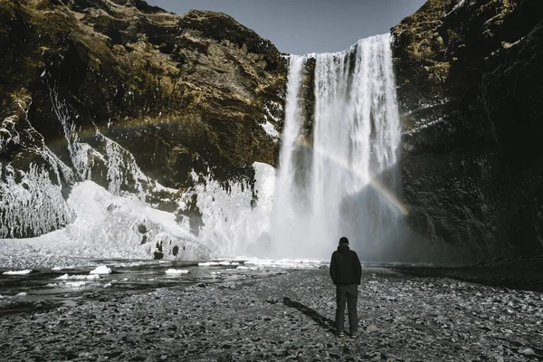 Ένα άτομο admirnig την ομορφιά της Skogafoss καταρράκτη με rainbow βρίσκεται στην Ισλανδία. — Φωτογραφία Αρχείου