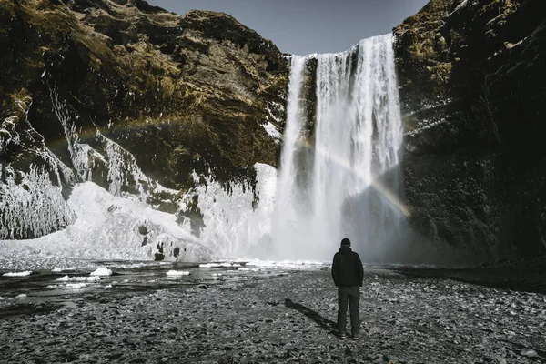 Una persona admira la belleza de la cascada de Skogafoss con arco iris situado en Islandia . —  Fotos de Stock