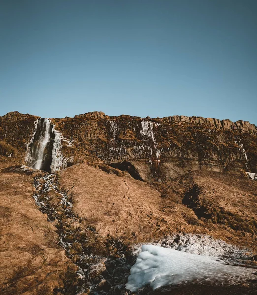 Maravilloso paisaje de Seljalandsfoss Cascada en Islandia en un día claro con cielo azul y nieve . — Foto de Stock