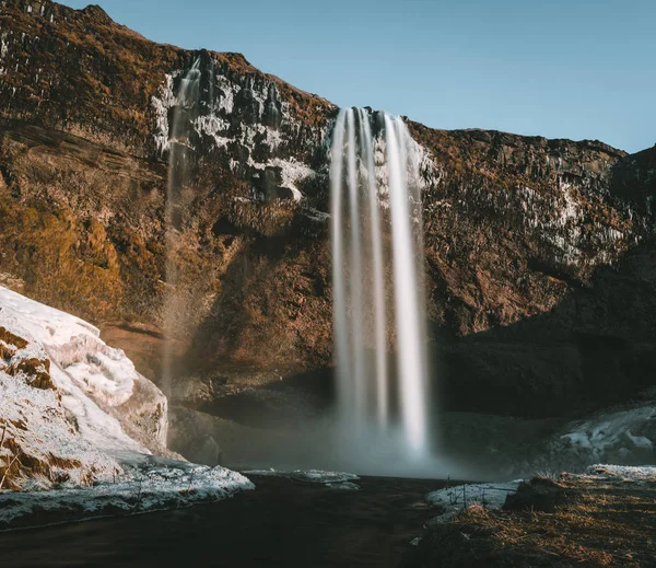 Wonderful landscape from Seljalandsfoss Waterfall in Iceland on a clear day with blue sky and snow. — Stock Photo, Image
