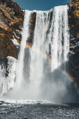 Mavi gökyüzü ile güneşli bir gökkuşağı ile İzlanda'daki Skogafoss şelale.