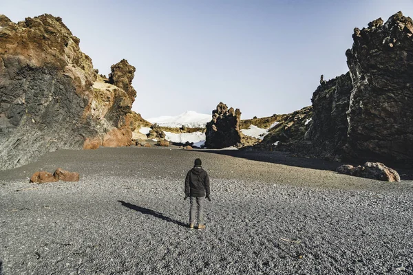 IJsland zwart strand zand jongeman toeristische reiziger met snaefellsnesjokull berg sneeuw blauwe hemel in de achtergrond. Westkant als het land. — Stockfoto