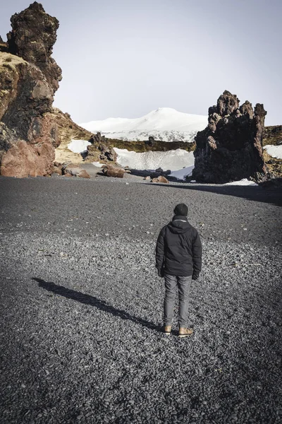 IJsland zwart strand zand jongeman toeristische reiziger met snaefellsnesjokull berg sneeuw blauwe hemel in de achtergrond. Westkant als het land. — Stockfoto