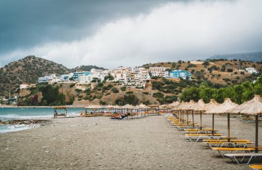 Saman şemsiye Yunanistan kumlu bir plaj üzerinde. Plaj sandalyeleri Crete adasında güzel bir plajda şemsiye ile.