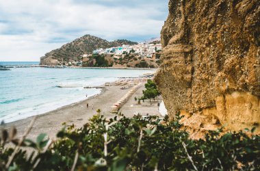 Crete, Yunanistan. Uçurumdan köyü deniz gemiler, tekneler ve deniz feneri ile görüntüleyin. Bay cliff beach ve Mimarlık - tatil tatil köyü ile açık okyanus su ile gelen görüntüleyin. Rethymno