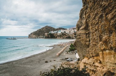 Crete, Yunanistan. Uçurumdan köyü deniz gemiler, tekneler ve deniz feneri ile görüntüleyin. Bay cliff beach ve Mimarlık - tatil tatil köyü ile açık okyanus su ile gelen görüntüleyin. Rethymno