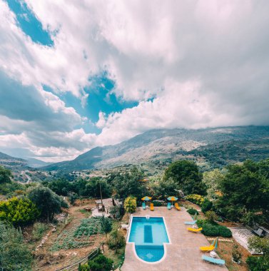 Arkadan Görünüş Lüks Villa yüzme havuzu ve şezlong dağlar ve mavi gökyüzü Crete, Yunanistan.