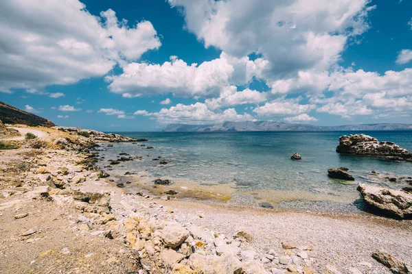 stock image Panoramic view of rocks and beach with sky and clouds in Crete, Greece. Amazing scenery with crystal clear water and the rock formation against a deep blue sky during Summer period. Greece, Europe