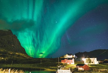 Aurora Norveç, Lofoten Adaları evde geleneksel kırmızı fisher üzerinde. Kuzey ışıkları Lofoten Adaları, Norveç. Yıldızlı gökyüzü Kutup ışıkları. Gece manzarası ile yeşil aurora borealis, kayalar
