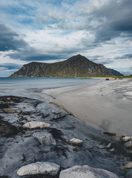 Kameny na pláži fjordu v norské moře v zimě pod sněhem. Skagsanden beach, modrá obloha a mraky v Lofoten ostrovy, Norsko — Stock fotografie