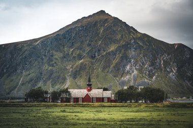 Flakstad Kilisesi 'nin arka planında dağlar var. Arktik, Flakstadoy, Lofoten Adaları, Kuzey Kutup Dairesi, Norveç' te XVIII.