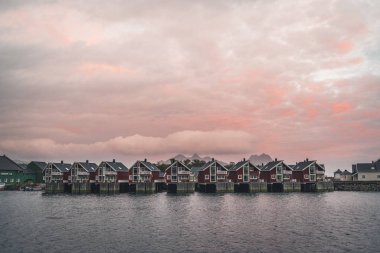 Svolvaer, Norveç - Eylül 2018: Kırmızı evleri waterfront içinde belgili tanımlık geçmiş gün batımı ile. Svolvaer Austvagoya Lofoten Adaları'nda bulunan balıkçı köyü ve turistik kasabası olan.