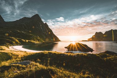 Sunstar dağlar içinde belgili tanımlık geçmiş Tangstad lofoten Adaları, Norveç'te yakınındaki plajda ile gün batımı. Dağ manzaralı güzel kumlu plaj.