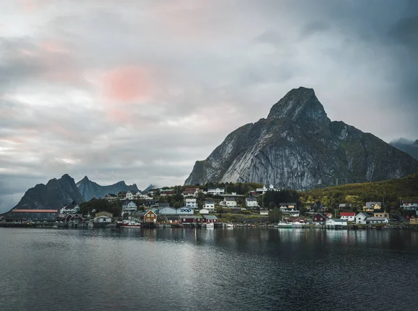 ノルウェー漁村レーヌでノルウェーのロフォーテン諸島。ドラマチックな夕焼け雲が夕暮れに急な山の峰の上に移動します。大西洋の通り光の反射. — ストック写真