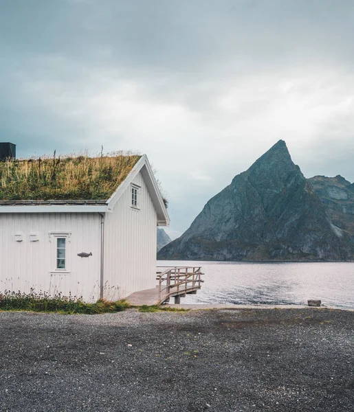 Lofoten eilanden Noorwegen - September 2018: Huis met traditionele grasdak en bergen op de achtergrond op een bewolkte dag. Lofoten is een archipel en een traditioneel district in het graafschap — Stockfoto