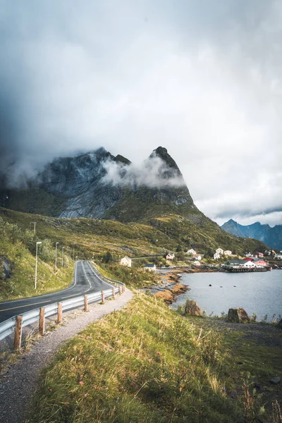 Viaje sinuoso por carretera hacia Reinebringen en Reine en las islas Lofoten con montañas en el fondo. Cielo nublado y malhumorado con océano atlántico . — Foto de Stock