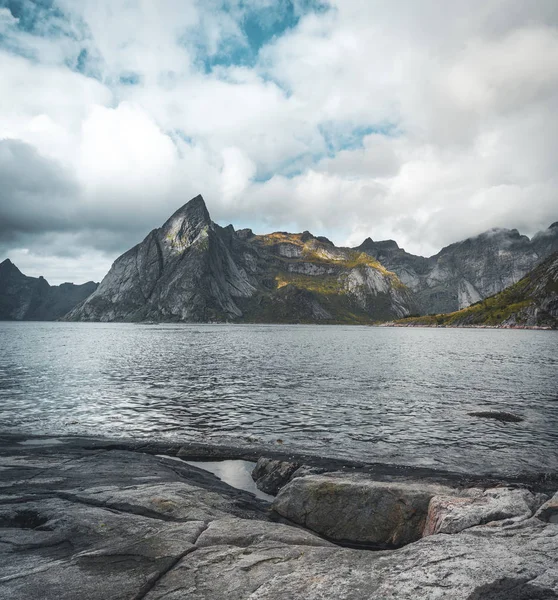 Lofoten Νορβηγία θέα προς βουνό με atantic στον ωκεανό και τους βράχους σε πρώτο πλάνο. Λαμβάνονται σε μια συννεφιασμένη μέρα με το μπλε του ουρανού. — Φωτογραφία Αρχείου
