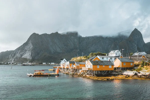 Casas rorbu amarelas de Sakrisoy vila piscatória em um dia nublado com montanhas no fundo. Lofoten Islands, Noruega — Fotografia de Stock