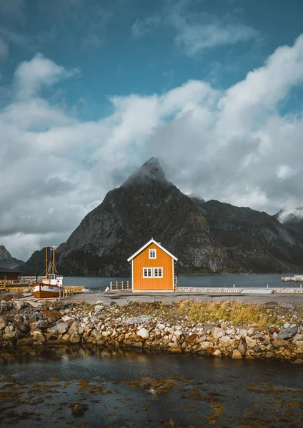 Casas rorbu amarelas de Sakrisoy vila piscatória em um dia nublado com montanhas no fundo. Lofoten Islands, Noruega — Fotografia de Stock