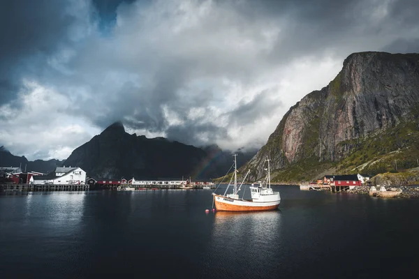 Reine, September 2018: Fartyget med regnbåge i bakgrunden i hamnen i kända turistattraktion Reine i Lofoten. — Stockfoto
