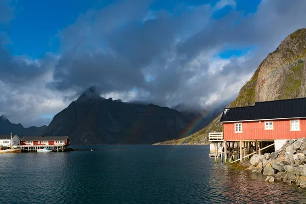 赤レインボー ofer 住宅赤がり家、雲、雨青い空とロフォーテン諸島、ノルウェーのレーヌの rorbuer、日当たりの良い。橋や山を背景に. — ストック写真