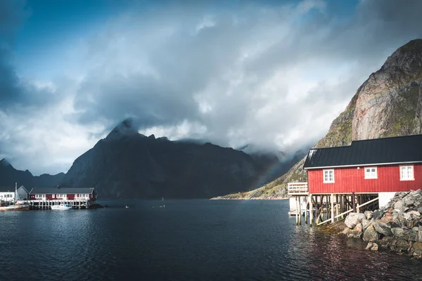 赤レインボー ofer 住宅赤がり家、雲、雨青い空とロフォーテン諸島、ノルウェーのレーヌの rorbuer、日当たりの良い。橋や山を背景に. — ストック写真