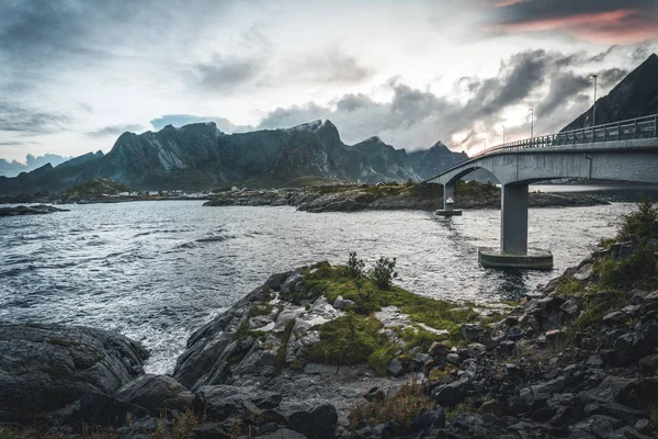 Vue du pont sur la mer et les montagnes dans les îles Lofoten, Norvège. Crête de Hamnoy au coucher du soleil en hiver. Paysage avec eau bleue, rochers dans la neige, route et ciel avec cloches. Vue du dessus — Photo