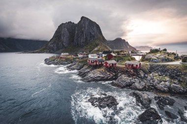 Bulutlar ve mavi gökyüzü ve okyanus dalgaları ile sonbahar günbatımı ünlü turistik cazibe Hamnoy balıkçı köyü Lofoten Adaları Reine, Norveç ile kırmızı rorbu Panoraması evler.