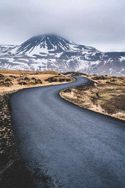 Perspectiva estrada sinuosa na Islândia com neve gama de montanhas fundo no dia nublado outono temporada Islândia . — Fotografia de Stock