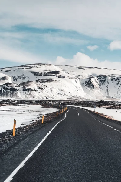 Perspective route sinueuse en Islande avec fond de chaîne de montagnes enneigées par temps nuageux automne Islande . — Photo