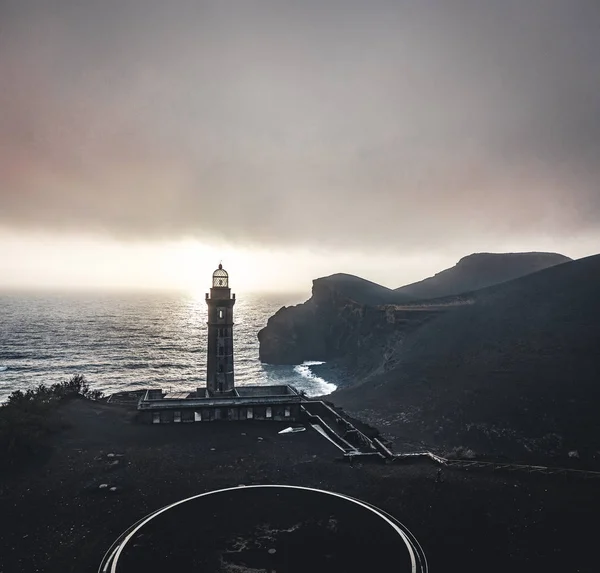 俯瞰卡佩利霍斯火山,蓬塔多斯卡佩利奥斯灯塔在法亚尔岛,亚速尔群岛,葡萄牙与戏剧性的日落和强烈的海浪和云。上一次火山爆发是在 — 图库照片