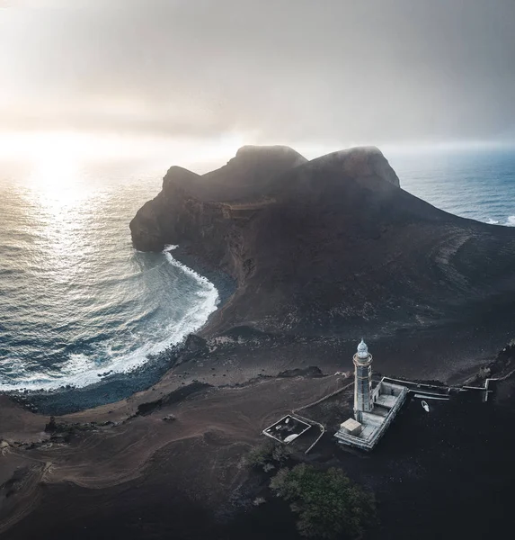 Blick über den Vulkan Capelinhos, Leuchtturm von Ponta dos Capelinhos an der Westküste der Insel Faial, Azoren, Portugal mit dramatischem Sonnenuntergang und starken Wellen und Wolken. letzter Vulkanausbruch war in — Stockfoto