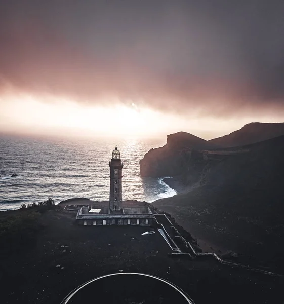 Vista sobre el volcán Capelinhos, faro de Ponta dos Capelinhos en la costa occidental en la isla de Faial, Azores, Portugal con una puesta de sol dramática y fuertes olas y nubes. Última erupción del volcán fue en —  Fotos de Stock