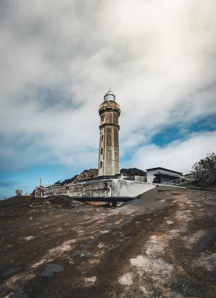 View over Capelinhos volcano, lighthouse of Ponta dos Capelinhos on western coast on Faial island, Azores, Portugal on a sunny day with blue sky and clouds and waves. Last volcano eruption was in 1957 — Stock Photo, Image