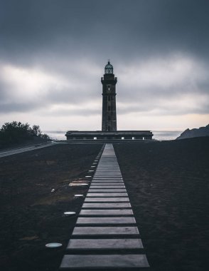 Capelinhos yanardağı, Faial adasında batı kıyısında Ponta dos Capelinhos deniz feneri, Azores, Portekiz dramatik bir gün batımı ve güçlü dalgalar ve bulutlar ile görünümü. Son yanardağ patlaması oldu