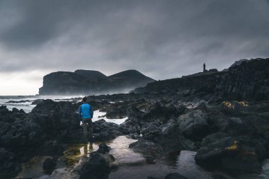 Capelinhos yanardağı, Faial adasında batı kıyısında Ponta dos Capelinhos deniz feneri, Azores, Portekiz dramatik bir gün batımı ve güçlü dalgalar ve bulutlar ile görünümü. Son yanardağ patlaması oldu