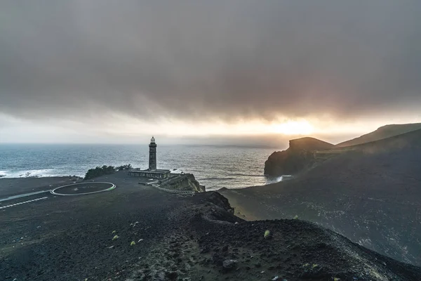 Bekijk de vulkaan Capelinhos, de vuurtoren van Ponta dos Capelinhos aan de westkust op het eiland Faial, de Azoren, Portugal met een dramatische zonsondergang en sterke golven en wolken. Laatste vulkaanuitbarsting was in — Stockfoto