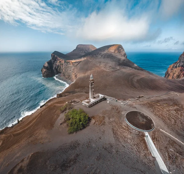 Вид на вулкан Капелиньюш, маяк Понта-душ-Капелиньюс на западном побережье острова Файал, Азорские острова, Португалия в солнечный день с голубым небом, облаками и волнами. Последнее извержение вулкана произошло в 1957 году — стоковое фото