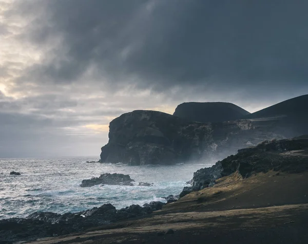 Blick über den Vulkan Capelinhos, Leuchtturm von Ponta dos Capelinhos an der Westküste der Insel Faial, Azoren, Portugal mit dramatischem Sonnenuntergang und starken Wellen und Wolken. letzter Vulkanausbruch war in — Stockfoto