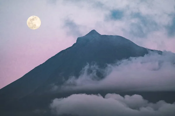Góra Pico wulkan zachodniego stoku oglądane z oceanu podczas pełni księżyca ze szczytu w chmurach po zachodzie słońca z różowe niebo, widziany z Faial Island w Azorach, Portugalia. — Zdjęcie stockowe