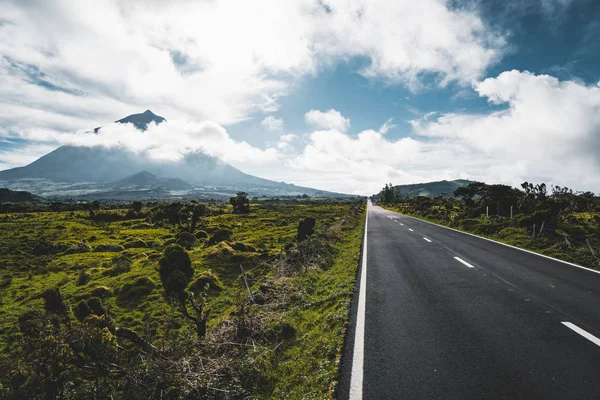 Camino longitudinal recto EN3 al noreste del Monte Pico y la silueta del Monte Pico a lo largo, isla de Pico, Azores, Portugal . — Foto de Stock