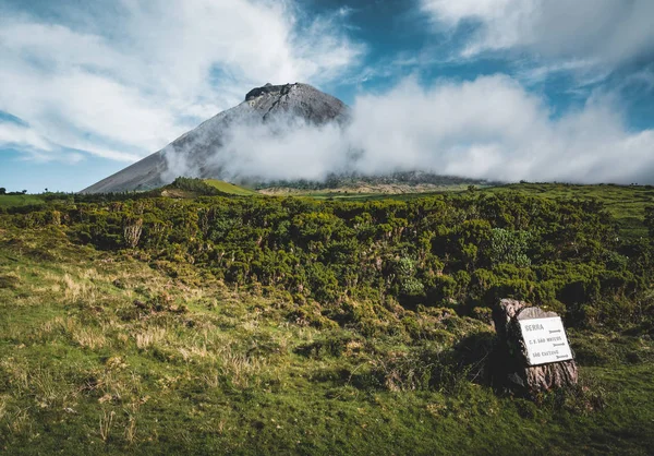 Pico Dağı'nın kuzeydoğusundaki Düz En3 uzunlamasına yol ve Pico Dağı'nın silueti, Pico adası, Azores, Portekiz.