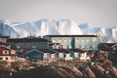 Grönland, Ilulissat 'ın Arktik şehrinin hava manzarası gün doğumunda sisle kaplandı. Kasabanın merkezinde renkli evler, yaz aylarında arka planda buzdağları, turuncu pembe ve güneşli bir günde.