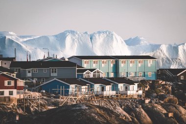 Aerial View of Arctic city of Ilulissat, Greenland during sunrise sunset with fog. Colorful houses in the center of the town with icebergs in the background in summer on a sunny day with orange pink clipart