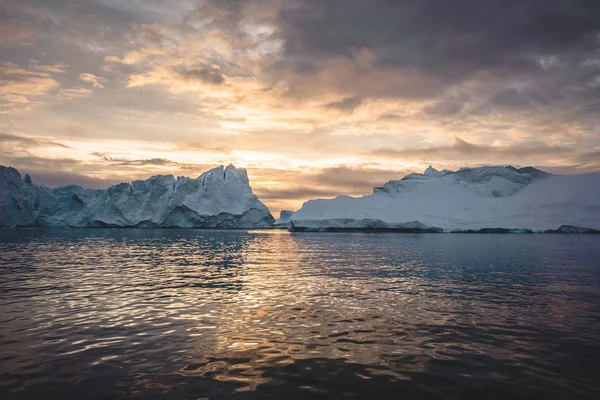 Paisagem natural do Árctico com icebergs no fiorde de gelo da Gronelândia com sol da meia-noite nascer do sol no horizonte. Alpenglow de verão de manhã cedo durante a temporada da meia-noite. Ilulissat, Gronelândia Ocidental. — Fotografia de Stock