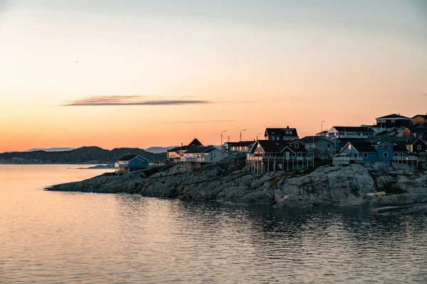 日出日落时，格陵兰的北极城市伊卢利萨的鸟瞰图。五颜六色的房子在镇中心与冰山的背景在夏天的阳光明媚的日子与橙色粉红色的天空 — 图库照片